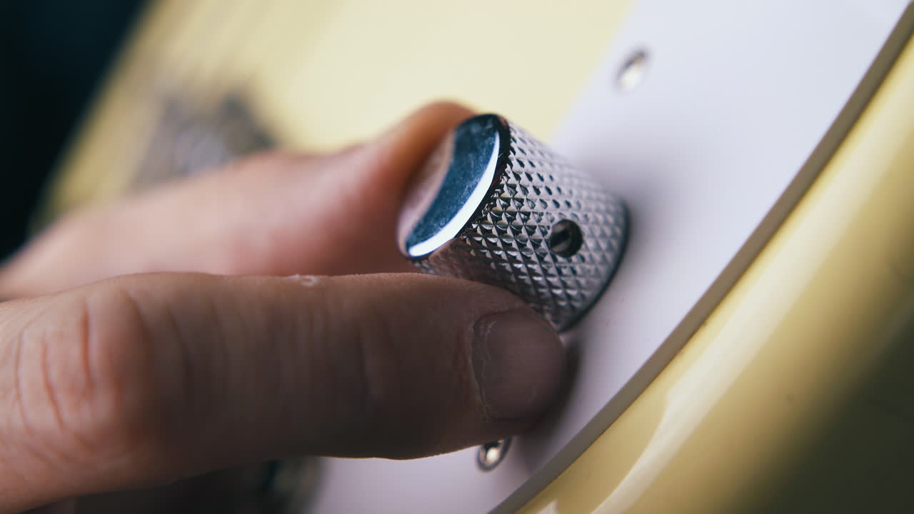a mão de um guitarrista profissional gira o botão de controle de volume