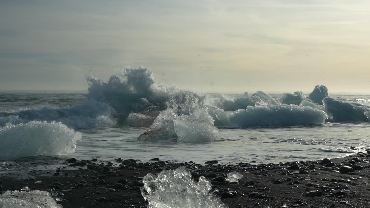 Gentle waves lap glacial ice fragments on Iceland's black sands at Diamond Beach