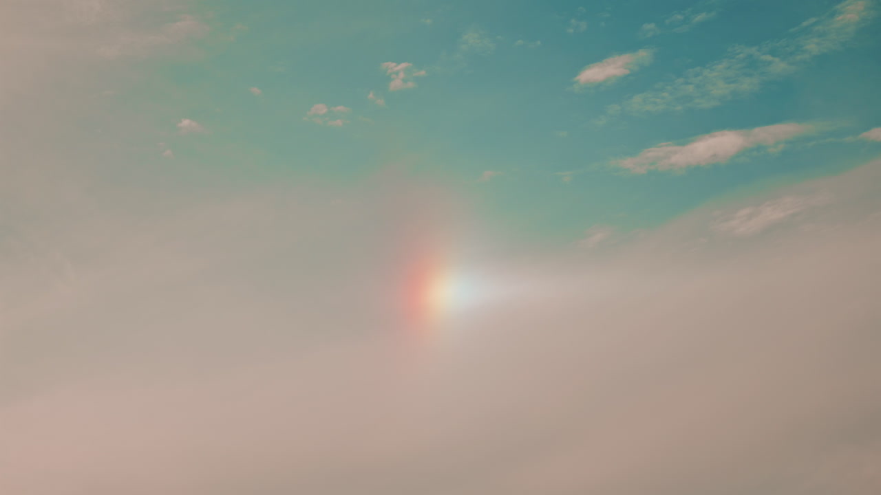 A subtle, soft sky with a faint vertical rainbow or sundog, blending warm and cool tones