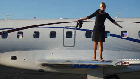 slomo: a playful flight attendant walks on the wing of an aircraft