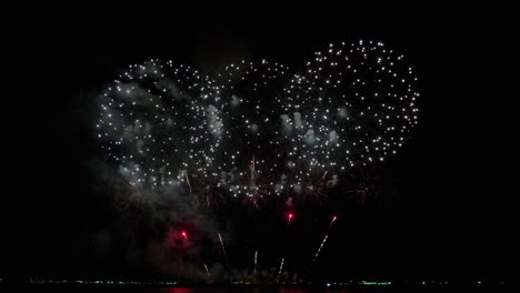 Gran-Diámetro-De-Explosiones-Blancas-Seguidas-Por-El-Mismo-Patrón-Pero-Comienza-Con-Naranja-Y-Luego-La-Base-Son-Chispas-Rojas,-Exhibición-De-Fuegos-Artificiales.