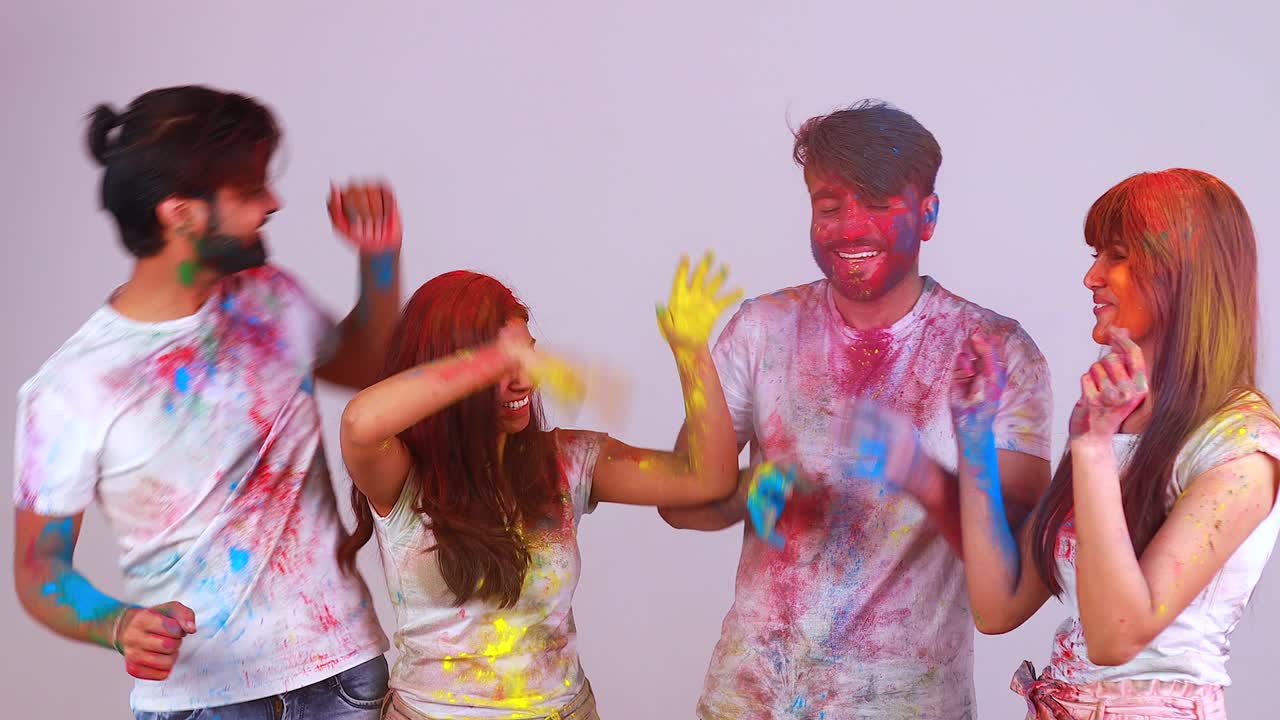 quattro migliori amici felici che trascorrono insieme un grande tempo tradizionale di holi in uno studio con sfondo bianco