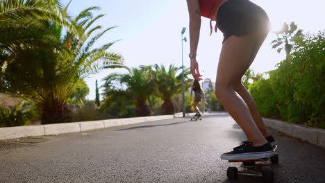 Mit-Palmen-Als-Zeugen-Fährt-Eine-Frau-Bei-Sonnenuntergang-Auf-Ihrem-Skateboard,-Ihr-Lächeln-Spiegelt-Die-Freude-An-Diesem-Gesunden-Lebensstil-Wider,-Auf-Dem-Sandweg-Im-Park