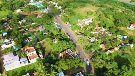 Bright-sunlight-on-rural-countryside-village-of-Karaikudi-as-motorbikes-drive-along-main-road