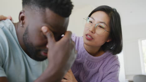 sad diverse couple sitting on couch and talking in living room