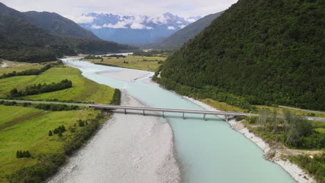 puente sobre un río glacial y altas montañas en el horizonte