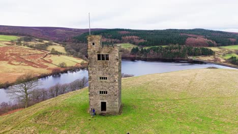 Old-derelict-castle,-monument,-disused-stone-tower,-with-people-walking-around-and-flying-a-drone