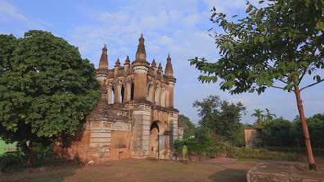 Feste-Aufnahme-Eines-Gebäudes-Und-Des-Baums-Daneben,-Wo-Eine-Frau-In-Grünem-Saree-Auf-Einer-Leeren-Straße-In-Sri-Lanka-Durch-Den-Eingang-Des-Gebäudes-Geht