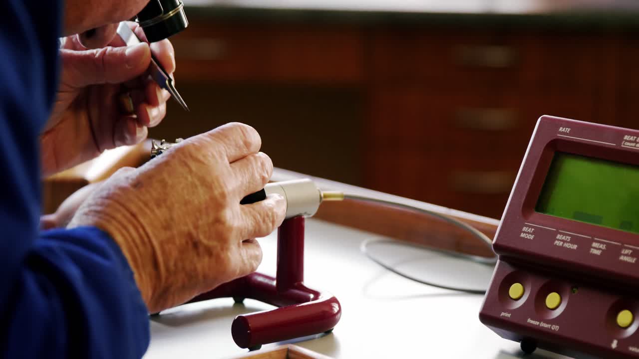 relojero reparando un reloj en una máquina