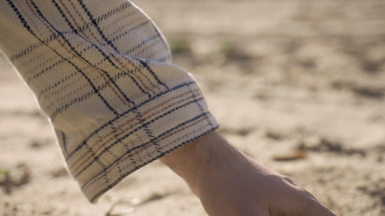 시골 에서 땅 에서 모래 를 집어 들고 있는 사람 의 손 의 근접적 인 모습