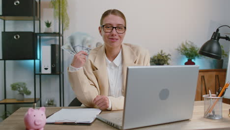 happy businesswoman working on office laptop rejoicing win receiving money cash success lottery luck