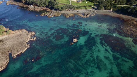 aerial push in on goat island marine reserve channel limpid turquoise water, new zealand