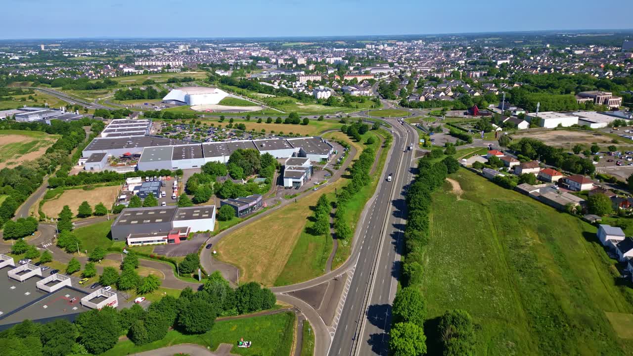 Forward drone movement over a semi-suburban highway road with commercial buildings and houses, Laval, Mayenne, France.