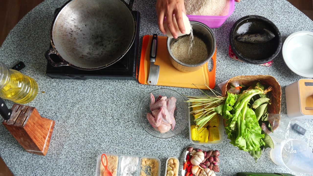 Lo chef versa il riso in una pentola di metallo per preparare gli ingredienti per un pasto tradizionale indonesiano in cucina.