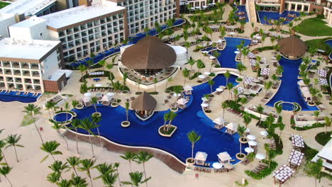 Pool-area-with-bars,-sun-loungers-and-palm-trees-in-luxury-vacation-resort-in-Dominican-Republic,-paradise-travel-destination-in-tropical-climate