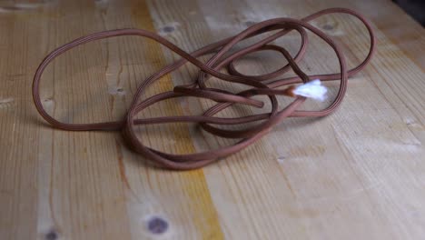 green paracord is thrown onto a light-colored wooden table and remains untouched