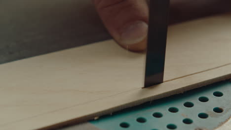 hands of woodworker cutting plank with bandsaw