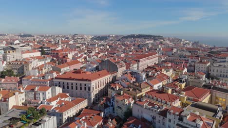 aerial slow pan across city and tall multi story buildings along lisbon portugal dense cityscape