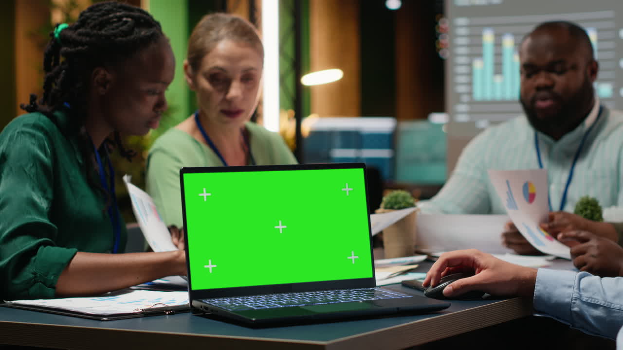 Diverse project team meeting after hours next to mockup display