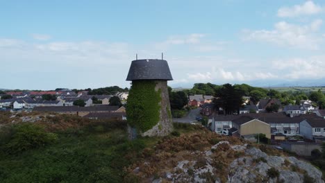 luftaufnahme vorbei an melin wynt y craig verlassene langefni windmühle mit efeu bedeckten hügeln wahrzeichen, um die walesischen snowdonia-berge zu enthüllen, anglesey