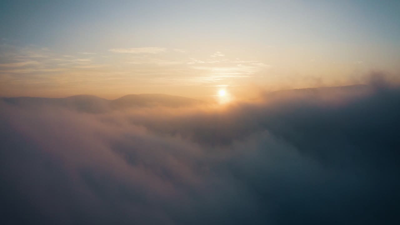 elevándose por encima de las nubes al atardecer con nubes y niebla mística, toma aérea de drones