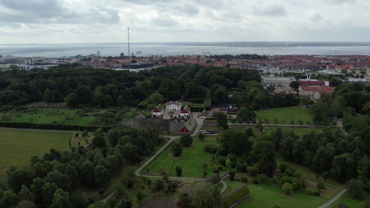 Fredriksdal Museum and Gardens, Helsingborg, Sweden - A Wide Aerial View Shows a Green Landscape with a Historic Estate and a Distant Coastal City - Aerial Drone Shot