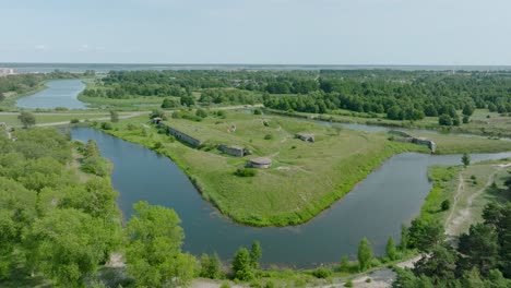 aerial establishing view of abandoned historical concrete seaside fortification buildings, southern forts near the beach of baltic sea in liepaja, sunny summer day, drone shot moving forward tilt down