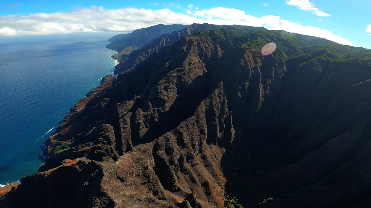하와이 카우아이의 구불구불한 언덕을 따라 푸른 해안선과 부서지는 파도의 공중 전망