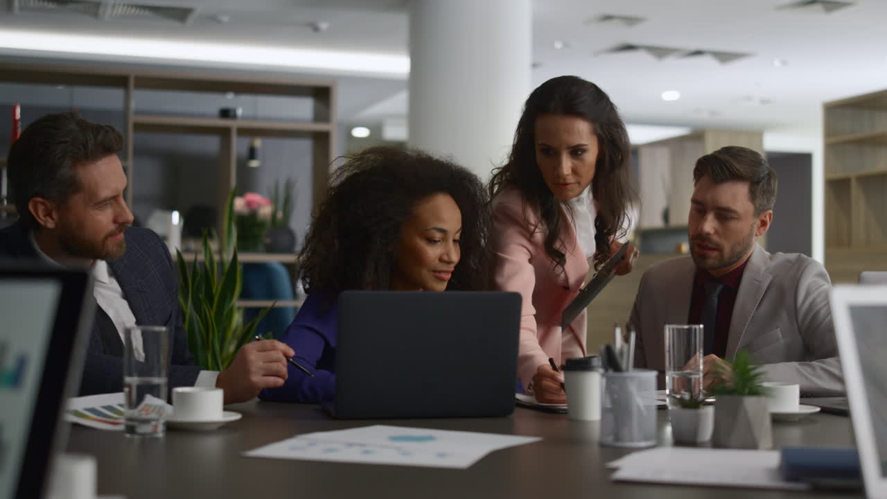 Multi ethnic emlpoyees working together using computer analyzing data on meeting