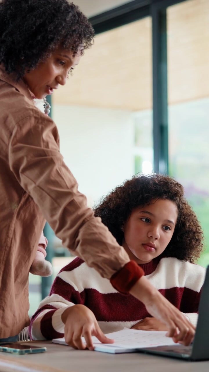 Mother Holding Baby While Helping Daughter With Homework
