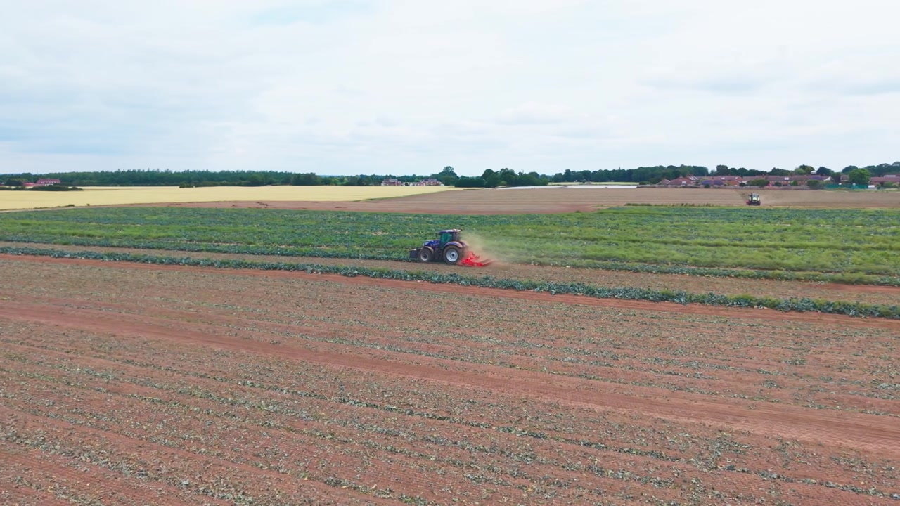 Aerial view of a tractor plowing a field at sunset. Working on Agricultural Field with Dust Trails and Plowed Soil Patterns farming soil preparation and crop cultivation, plowing farmland UK