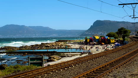 slow dolly approach next to train tracks of tide pool and colorful victorian-style bathing boxes on st