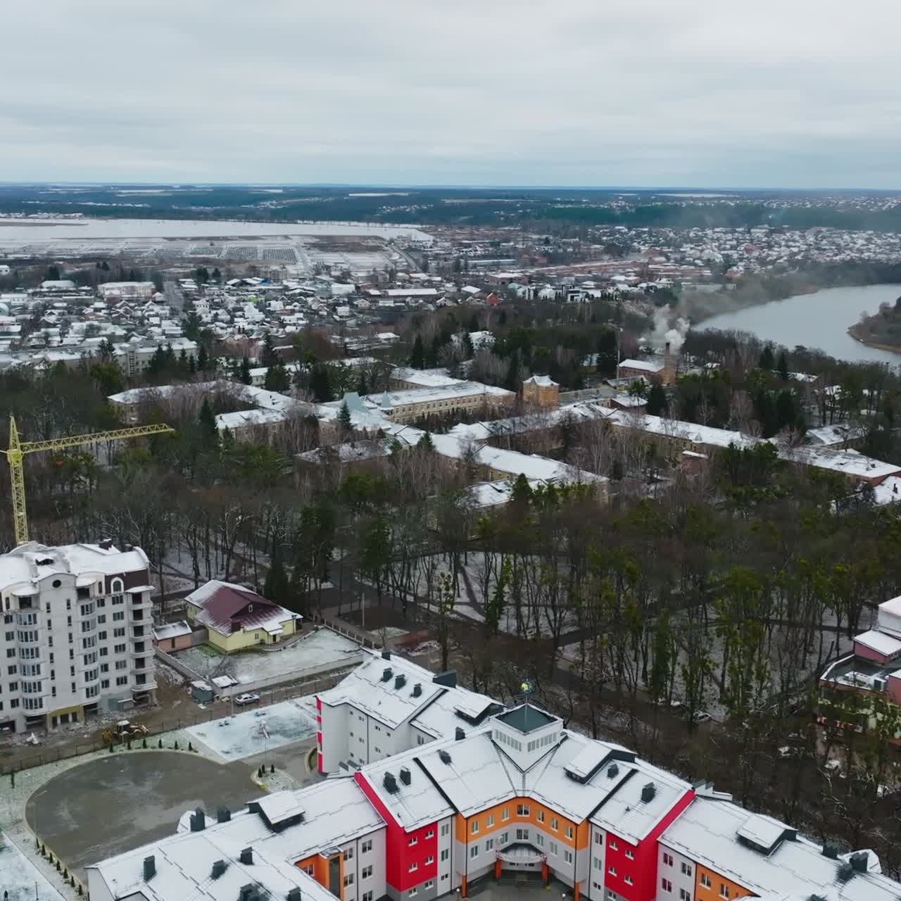 New unusual building of a city school. Creative bright design of a school building in a new residential district. Cityscape and river at the background