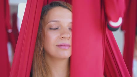 concentrada mujer bonita se sienta relajada en una hamaca de yoga de mosca