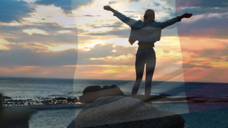 animation der italienischen flagge über einer glücklichen kaukasischen frau mit ausgestreckten armen am sonnenuntergang am strand