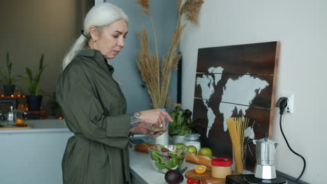 senior woman preparing a salad in the kitchen