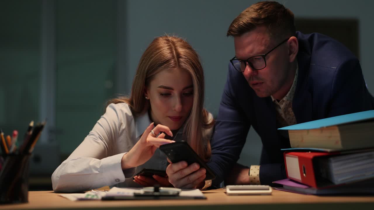 Colleagues looking at a smartphone together in an office
