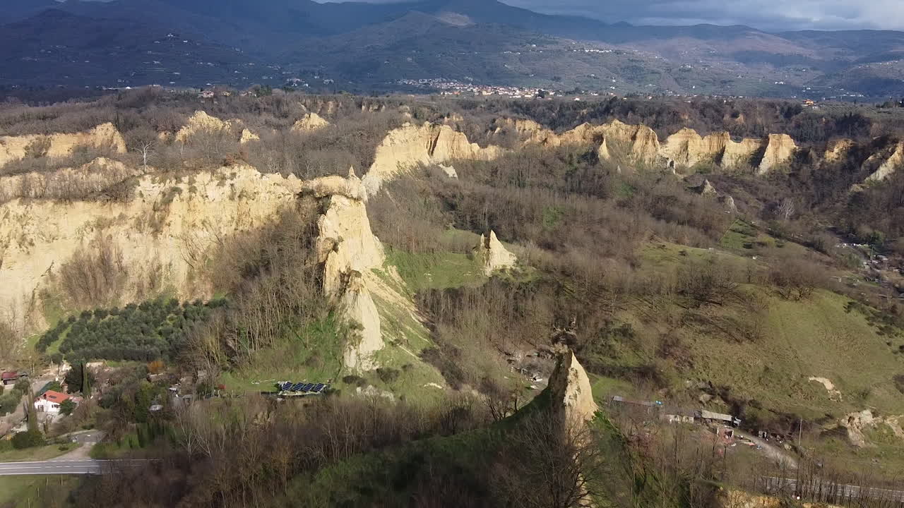 Aerial flying drone shot over prehistoric age canyons during winter Le Balze natural reserve near Reggello. Tuscany, Chianti area. Italy. Partially sunny sunset.
