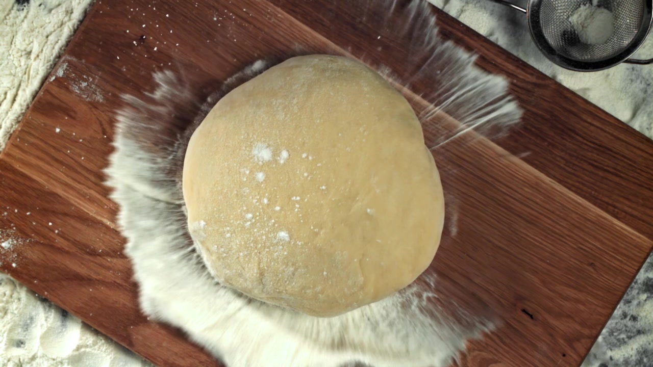 Slow Motion of Flour Sprinkling on Dough on a Wooden Board