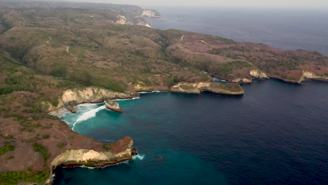 Ripresa aerea di onde oceaniche turchesi che si infrangono sulla costa della Broken Beach, famoso luogo turistico sull'isola di Nusa Penida, Indonesia