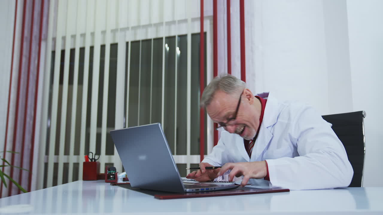 Online consultation in health service. Medical specialist giving a training talk in front of laptop gesticulating a lot. Senior doctor explains treatment to a patient during distant meeting.