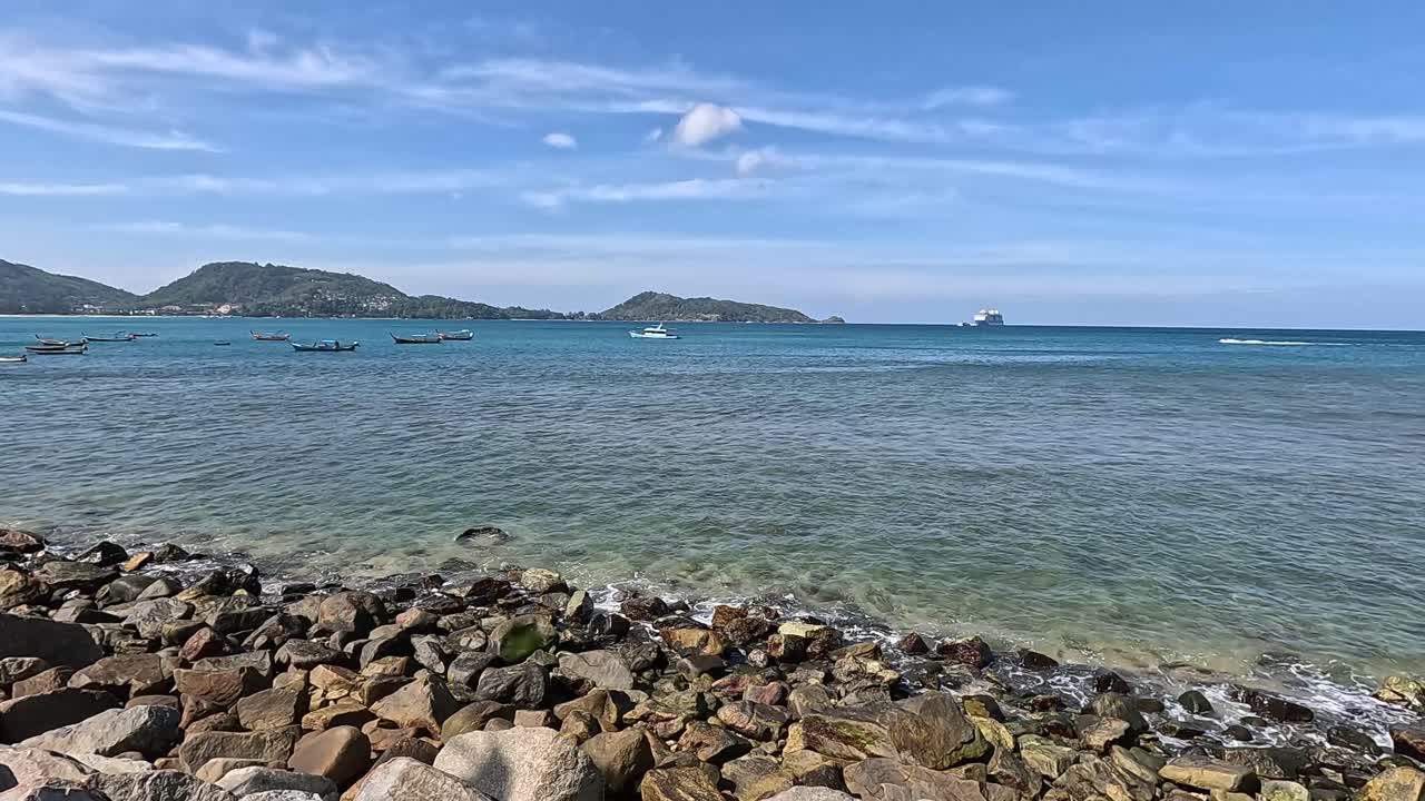 A tranquil seaside scene with rocky shores and clear blue waters under a bright sky in Phuket, Thailand