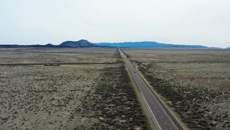 Road-trip-through-deserted-area-highway-with-mountains-in-distance