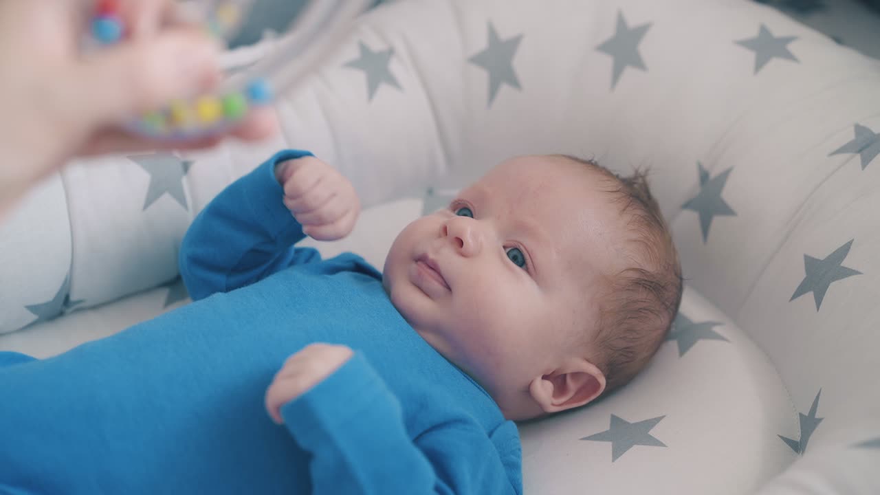 el bebé feliz molesta los brazos mirando el cascabel en el capullo