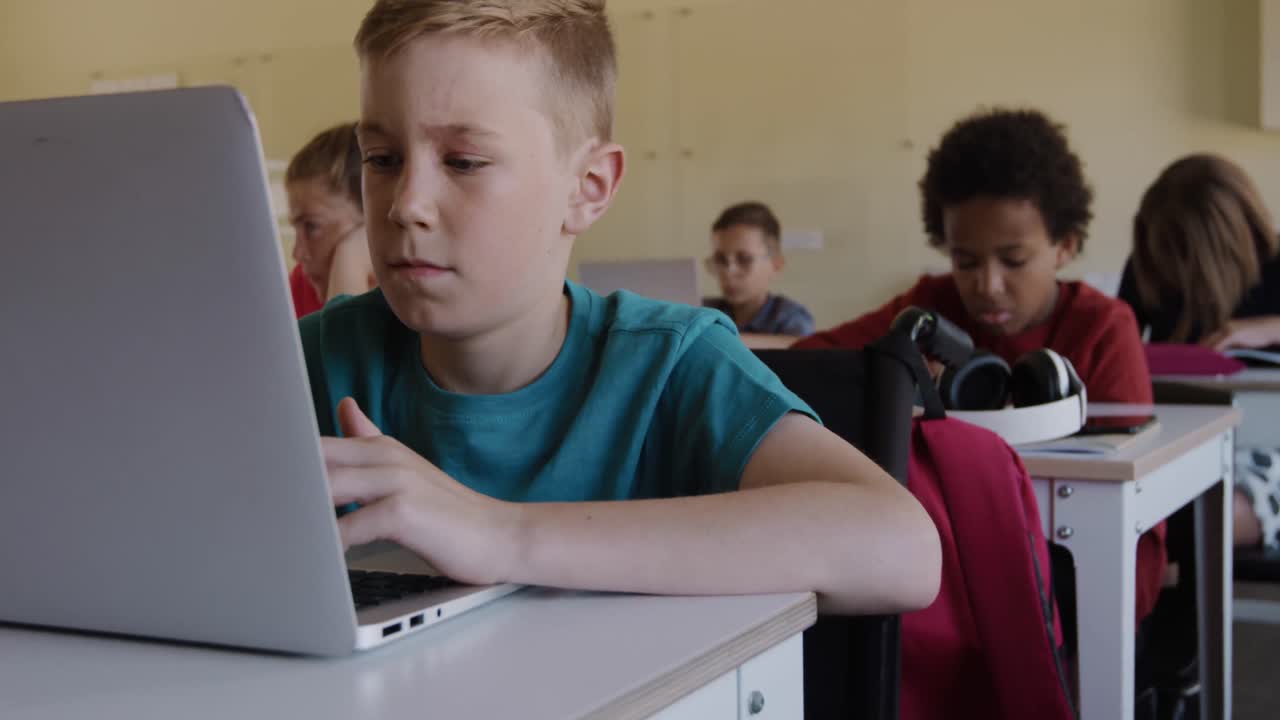 niño con discapacidades físicas que usa una computadora portátil en la clase