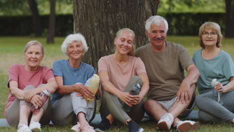 portrait of happy senior people and female fitness instructor in park