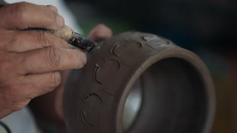 artisan carving a clay pot