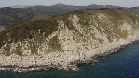 Bird's-eye-view-of-a-breathtaking-steep-rocky-coast-line-and-a-deep-blue-ocean