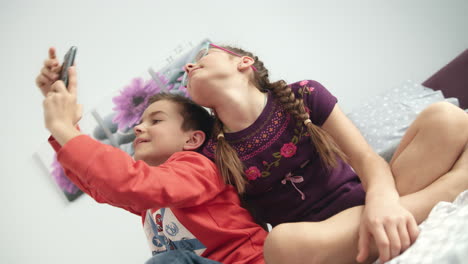 Niños-Tomando-Fotos-Selfie-En-Teléfonos-Móviles.-Selfie-De-Niños-En-Casa