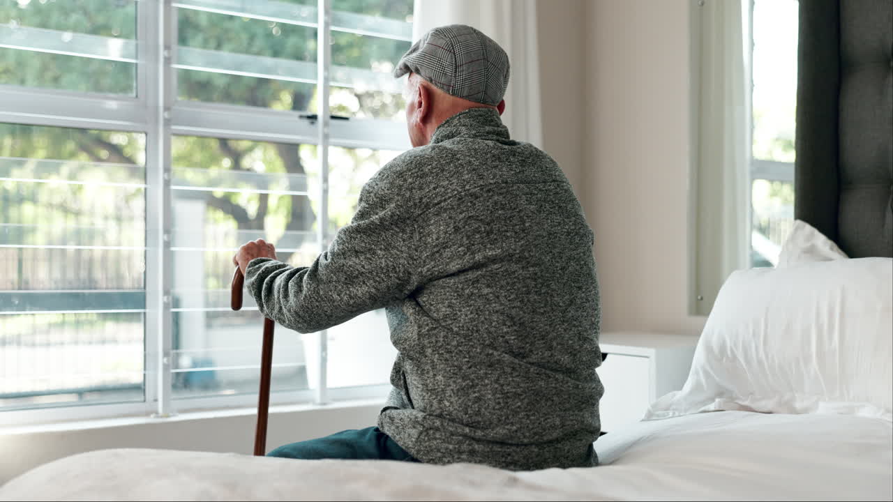 Elderly man with cane looking out the window